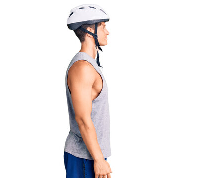 Young handsome man wearing bike helmet looking to side, relax profile pose with natural face with confident smile.