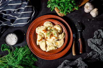 Dumplings, filled with mashed potato on dark background. Varenyky, vareniki, pierogi, pyrohy - dumplings with filling