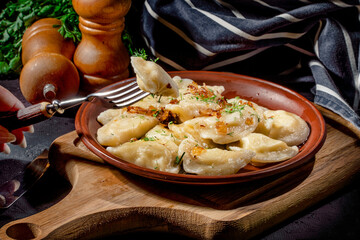 Dumplings, filled with mashed potato on dark background. Varenyky, vareniki, pierogi, pyrohy - dumplings with filling
