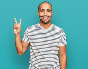 Fototapeta premium Hispanic adult man wearing casual clothes showing and pointing up with fingers number two while smiling confident and happy.