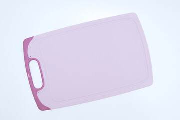 Kitchen pink cutting plastic board on white table.