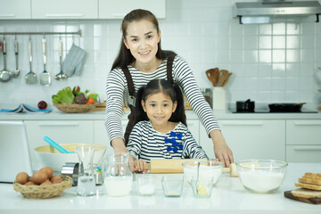 Portrait of young asian wmother and daughter baking and cooking in kitchen,activity of family at school holiday.