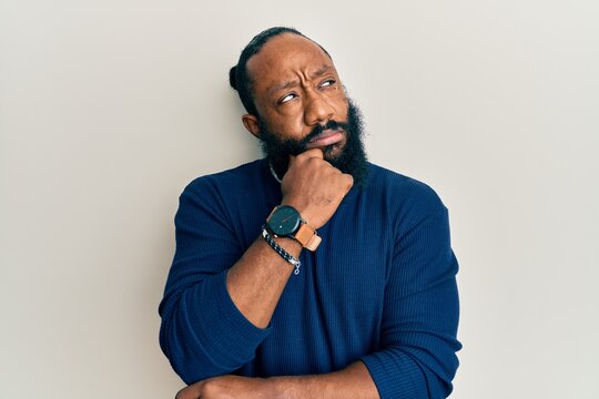 Young african american man wearing casual clothes thinking concentrated about doubt with finger on chin and looking up wondering
