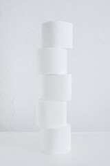 Rolls of toilet paper on table against a white wall background.