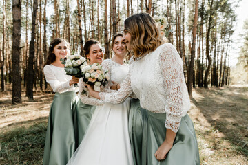 Tender bride with smiling bridesmaids dressed in long elegant dresses,bridesmaids with happy bride...
