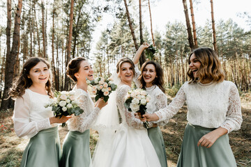 Tender bride with smiling bridesmaids dressed in long elegant dresses,bridesmaids with happy bride...