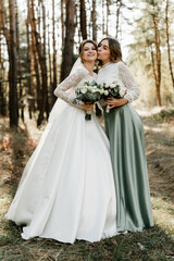 Obraz na płótnie Canvas Tender bride with smiling bridesmaids dressed in long elegant dresses,bridesmaids with happy bride on wedding day. wedding bouquets are held by girlfriends, wedding day,