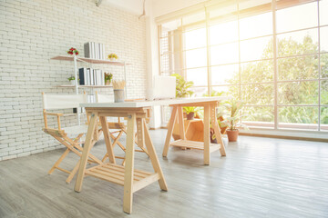 Brown wooden floor between pouf and grey sofa in white home office interior with chair at desk. Real photo