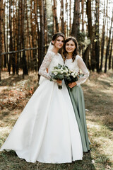Obraz na płótnie Canvas Tender bride with smiling bridesmaids dressed in long elegant dresses,bridesmaids with happy bride on wedding day. wedding bouquets are held by girlfriends, wedding day,