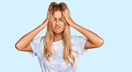 Beautiful blonde young woman wearing casual tie dye shirt suffering from headache desperate and stressed because pain and migraine. hands on head.