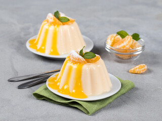 Creamy mandarin pudding with citrus sauce on a plate on a light gray background