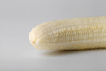 One peeled banana on a white background close-up