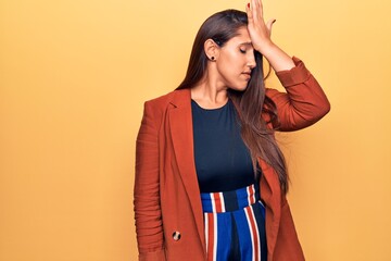 Young beautiful brunette woman wearing elegant jacket surprised with hand on head for mistake,...