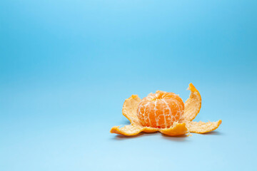 Peeled tangerine on a blue background. Mandarin in an unusual shape