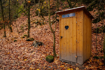 Countryside wooden toilet in a village, old door with a heart in the forest, Hiking Golden Trail of Bohemian Paradise near Vranov castle and Pantheon, Mala Skala, Czech Republic