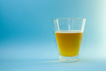 Beer in a glass on a blue background. Brown liquid from a glass.