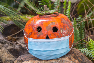 Ornamental ceramic Halloween pumpkin wears a covid-19 mask image in horizontal format
