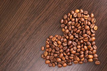 Heart shape made from coffee beans. Roasted Coffee beans background close up. International coffee day concept
