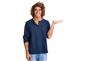 Young hispanic man wearing casual clothes smiling cheerful presenting and pointing with palm of hand looking at the camera.