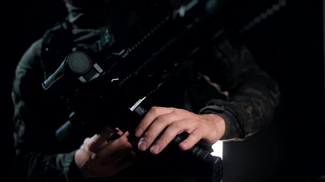 Soldier in a camouflage uniform attaches a magazine with cartridges to his weapon