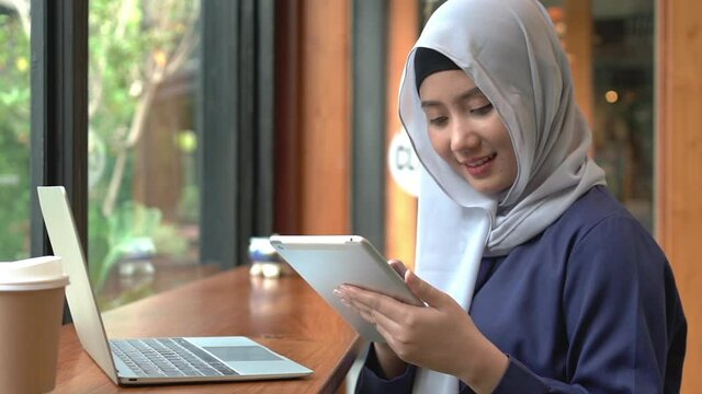 
Islamic women smile with happy her work for private business in cafes with computer laptop and tablet