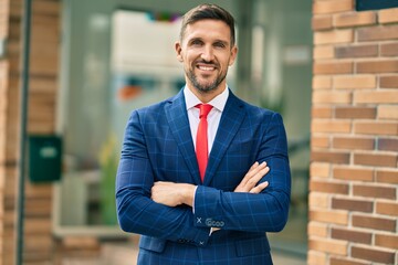 Young caucasian businessman with crossed arms smiling happy at the city.