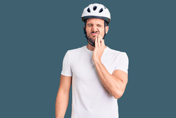 Young handsome man wearing bike helmet touching mouth with hand with painful expression because of toothache or dental illness on teeth. dentist