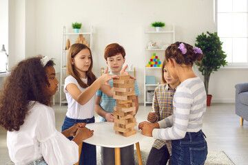 Mixed race children friends playing building pyramid of wooden details together