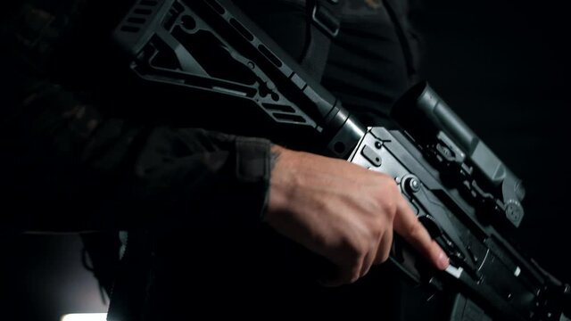 Man in a multicam on a black background puts the fuse box on the AK into a firing position 