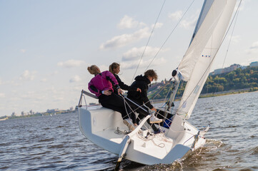 A mixed crew of a sports yacht participates in sailing competitions on the river. One man and two...