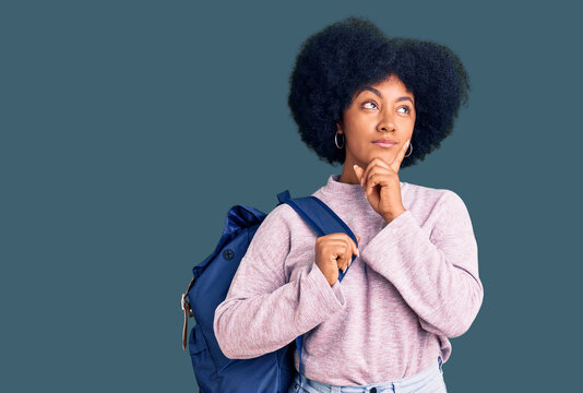 Young african american girl holding student backpack serious face thinking about question with hand on chin, thoughtful about confusing idea