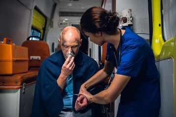 A female paramedic checking her patient's pulse, the patient is having an oxygen mask on.