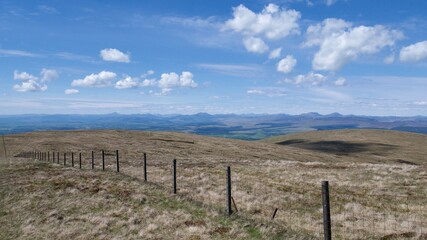 Fototapeta na wymiar fence between pastures on top of Scottish hills on a hot summer day