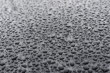 Water, rain drops on a smooth black glass surface