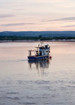 Sunset in Alloa harbour overlooking river Forth with fishermen boats and Stirling Castle and Scottish hills in the background