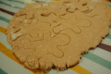 raw cookies made from cottage cheese and rice flour with date syrup in the shape of a gingerbread man cooked in the process of cooking at home side view