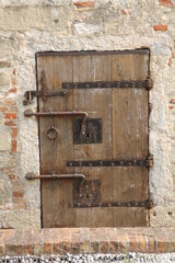 old wooden entrance door, with forged metal, hinges and latches, bolts