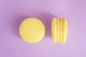 Two tasty yellow macarons on the purple background.