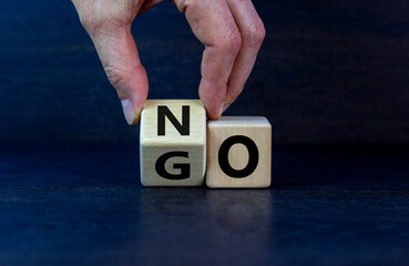 No or go. Hand flips a cube and changes the word 'no' to 'go'. Beautiful grey background. Business...