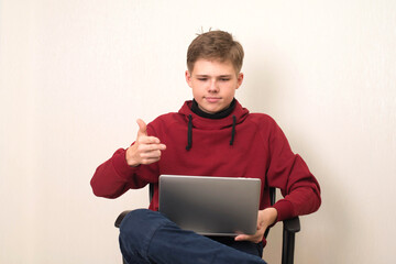 Portrait of a young teenager boy using laptop isolated over white wall.