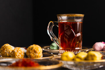 Tea with saffron, dates with chocolate on black background