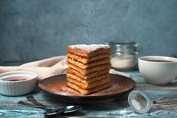 French waffle cake on a blue-gray background. The concept of desserts. Side view.