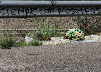 Road accident mourning scene with posthumous flowers and text on road bars