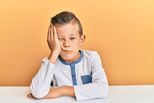 Adorable caucasian kid wearing casual clothes sitting on the table thinking looking tired and bored with depression problems with crossed arms.