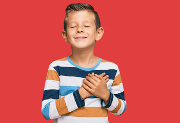 Adorable caucasian kid wearing casual clothes smiling with hands on chest with closed eyes and...