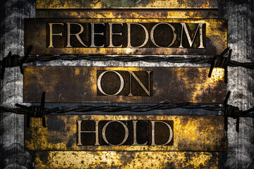 Freedom On Hold text lined with barbed wire on textured grunge copper and vintage gold background
