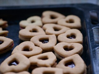 Heart shaped jam filled butter cookies on a baking tray