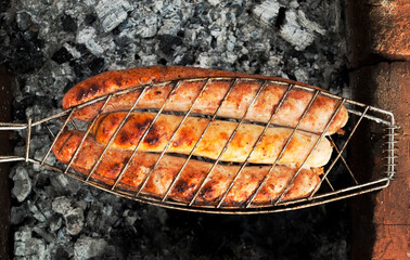 Sausages, sausages, fried in a net over a fire. Outdoor barbecue.