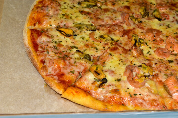 Round delicious sea pizza with seafood in a box