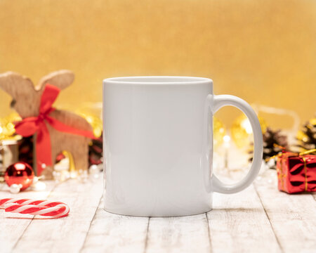 White Ceramic Coffee Mug And Christmas Decoration On Table Background And Gold Backdrop. Mockup For Creative Advertising Text Message Or Promotional Content. Mock Up For Mugs Cups POD